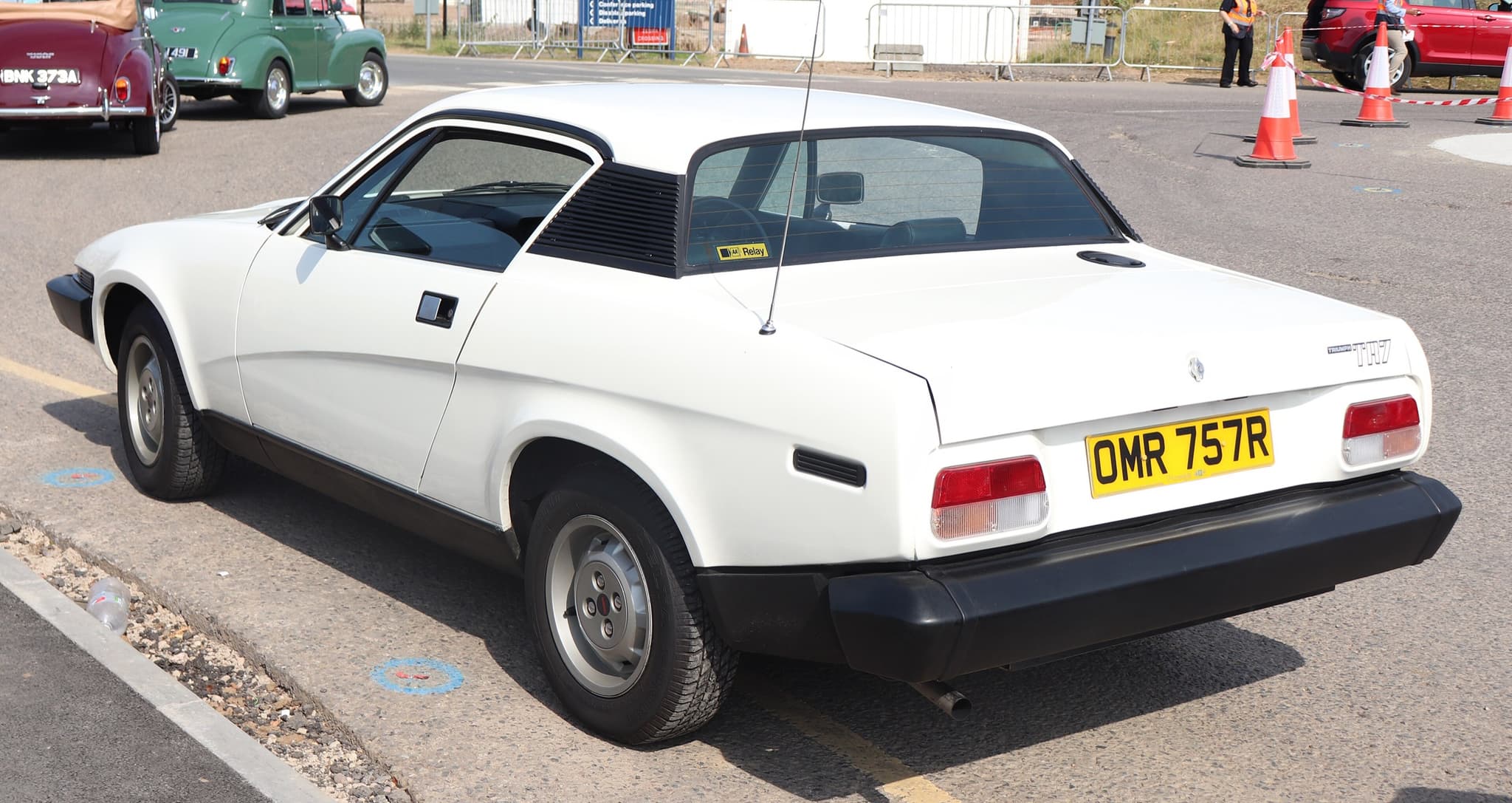 A white coupé seen from behind and to one side, with TRIUMPH and TR7 lettering across the tail. Opens a larger view