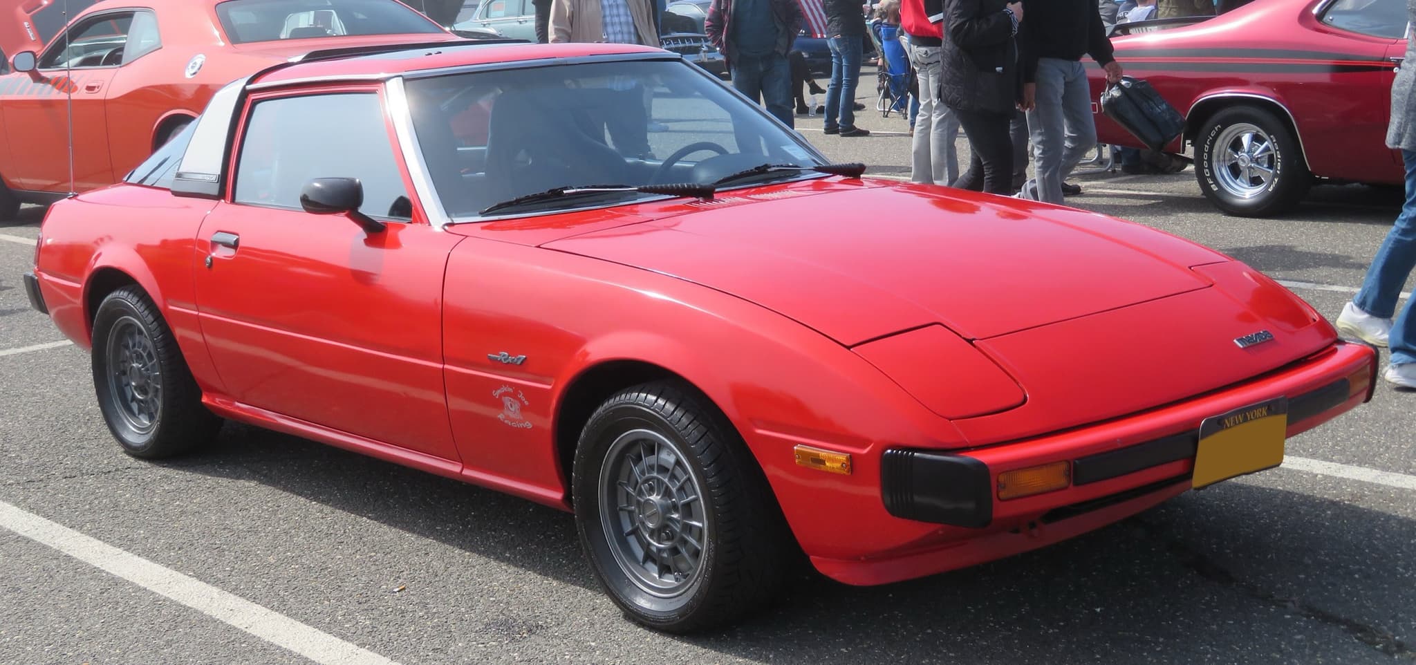 A red coupé with pop-up headlamps, front three-quarter.
