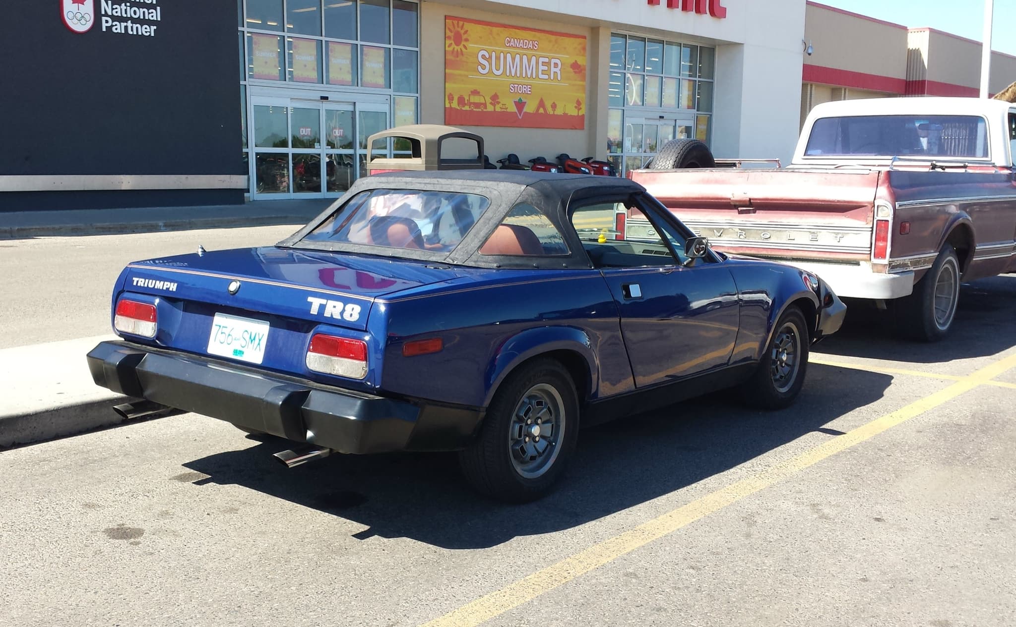 The tail of a blue convertible with a TR8 badge and twin exhaust pipes.