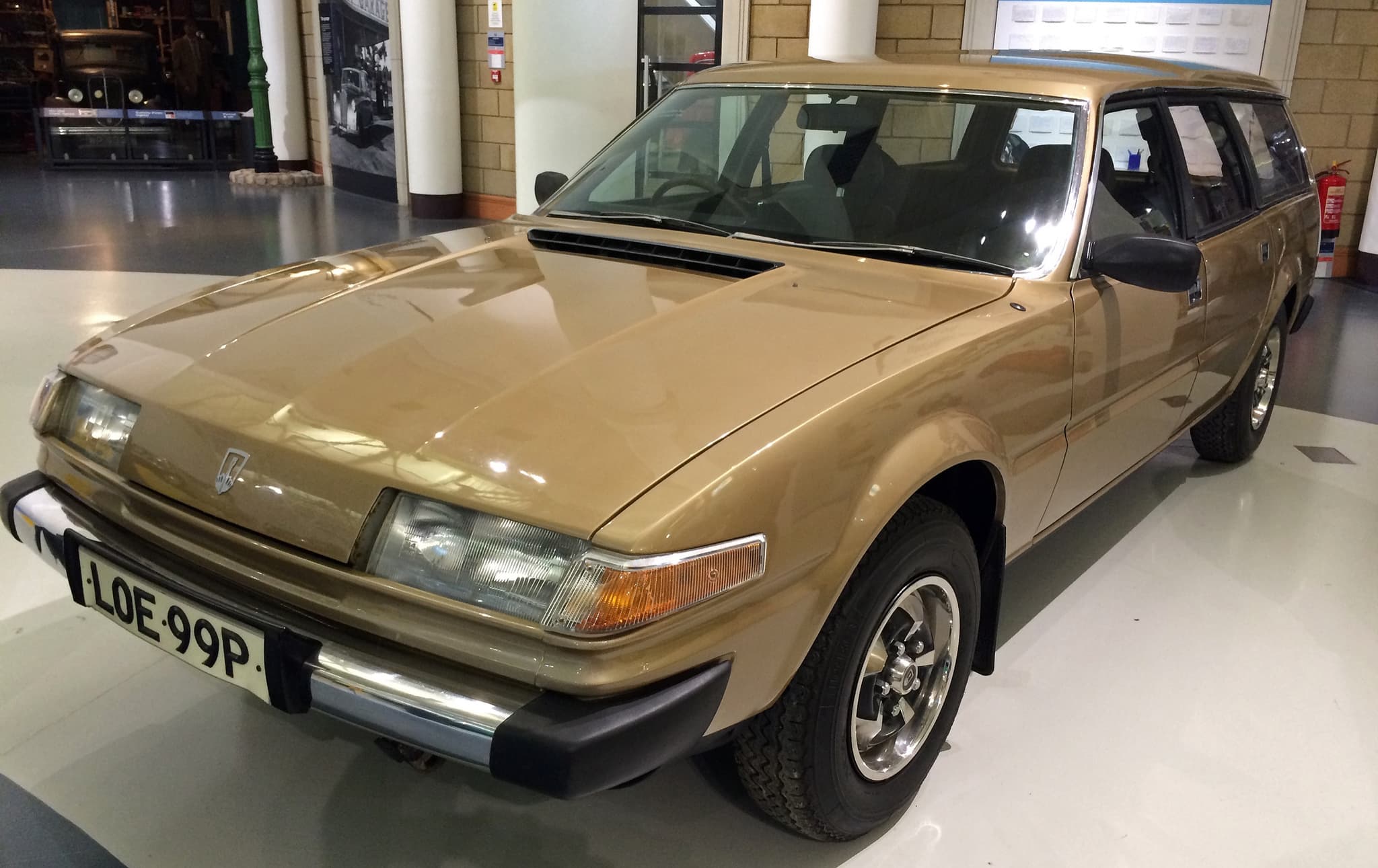 A gold hatchback estate prototype on display in a museum hall.